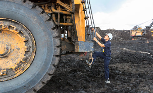 Man climbing onto huge digger in quarry